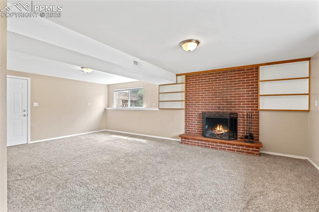 Image 16 of 40: Unfurnished living room featuring carpet and a brick fireplace