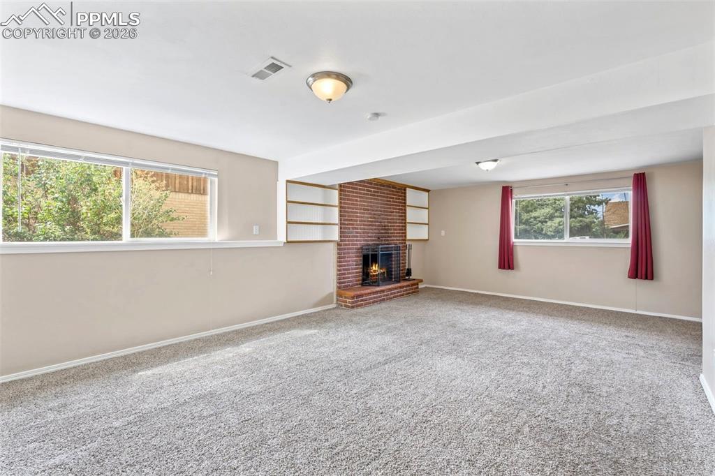 Image 17 of 40: Unfurnished living room featuring carpet floors and a brick fireplace