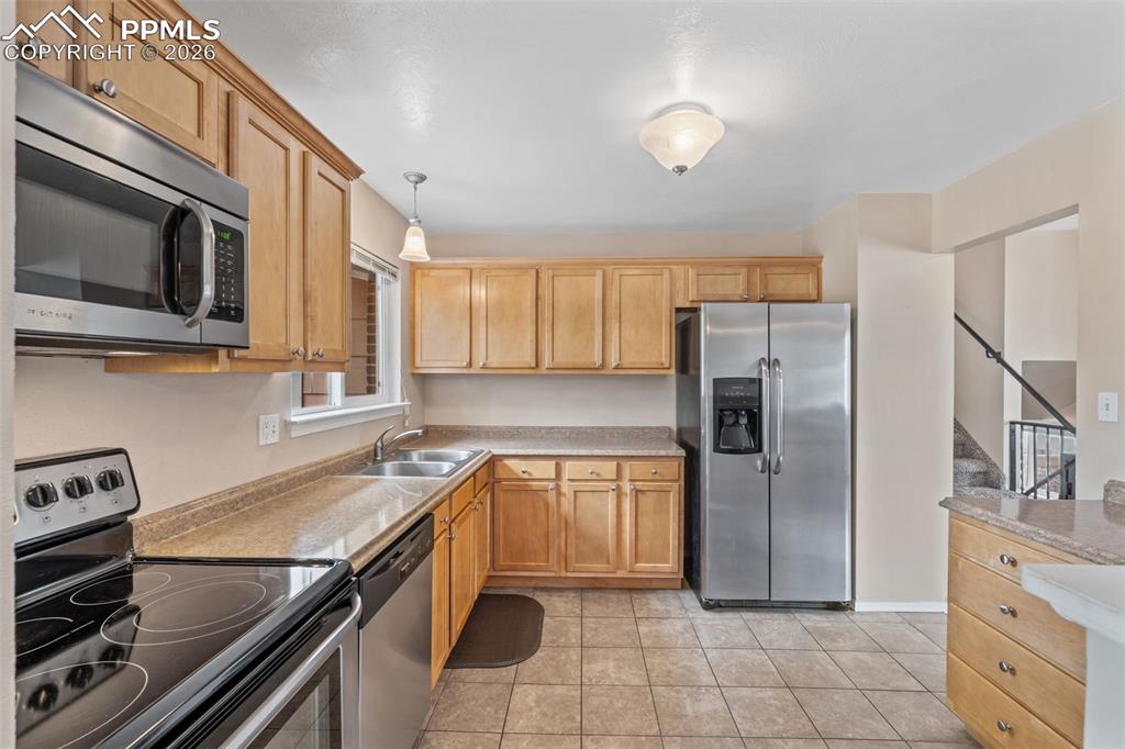 Image 3 of 40: Kitchen featuring stainless steel appliances, light countertops, hanging li