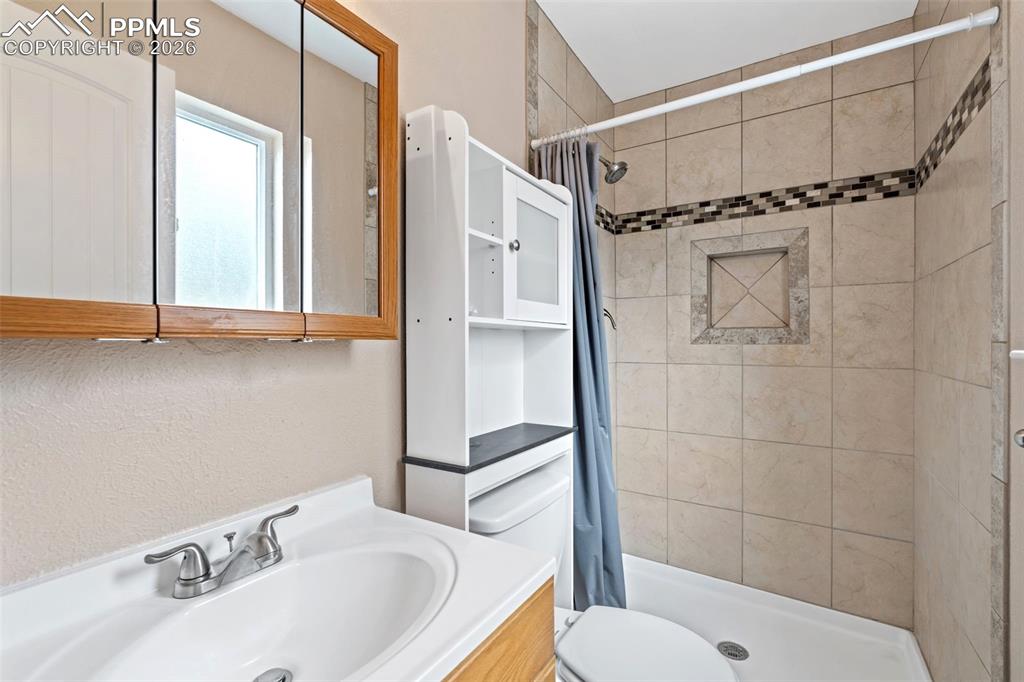 Image 37 of 40: Full bathroom featuring vanity, a stall shower, and a textured wall