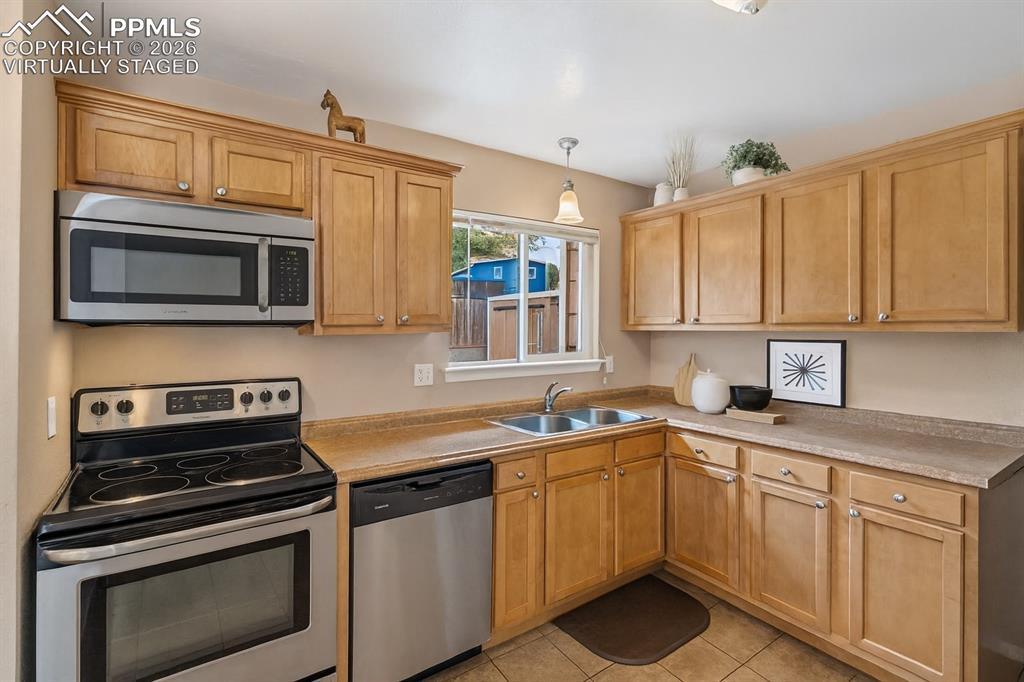 Image 4 of 40: Kitchen with stainless steel appliances, light countertops, decorative ligh