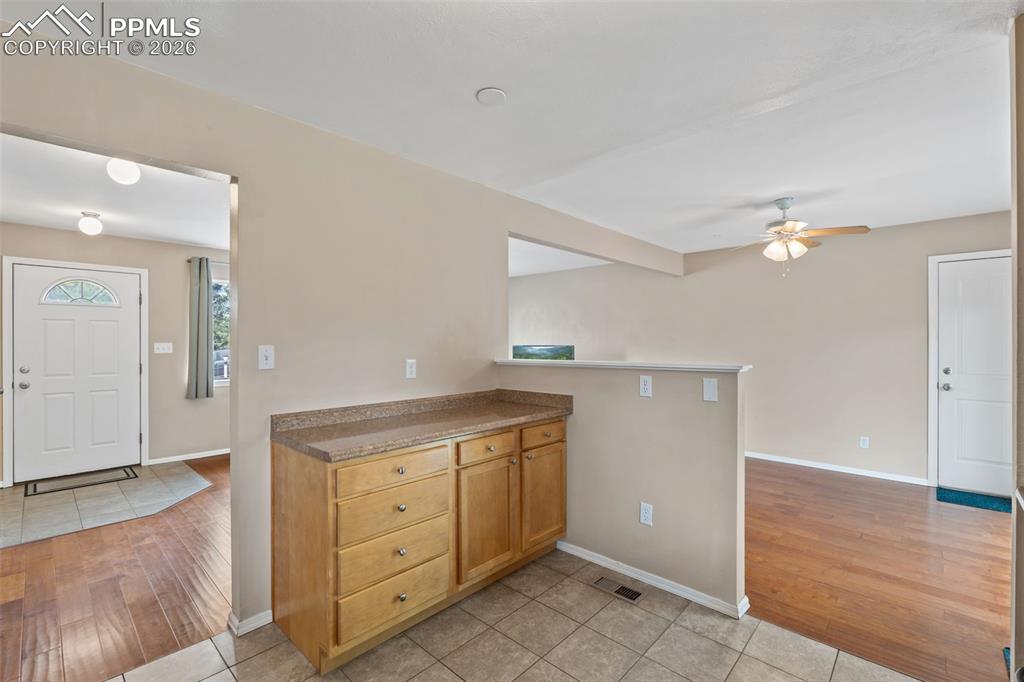 Image 7 of 40: Kitchen with light tile patterned floors, ceiling fan, a peninsula, and woo