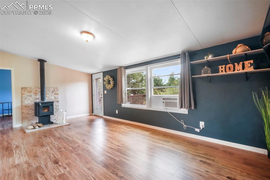 Image 16 of 50: Unfurnished living room with a wood stove and wood finished floors