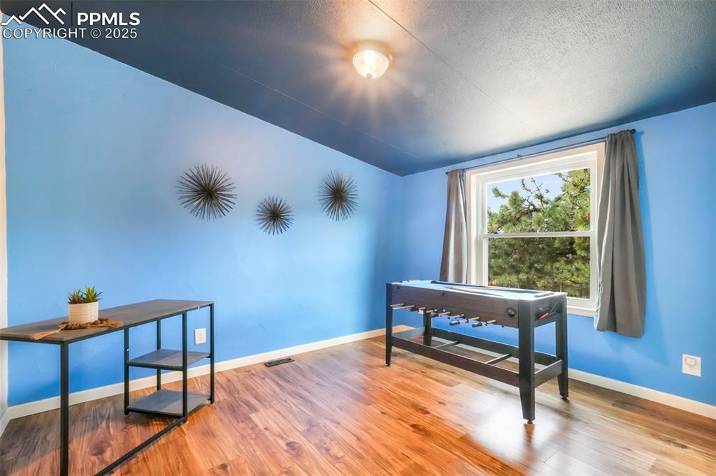 Image 30 of 50: Office space featuring wood finished floors, a textured ceiling, and vaulte