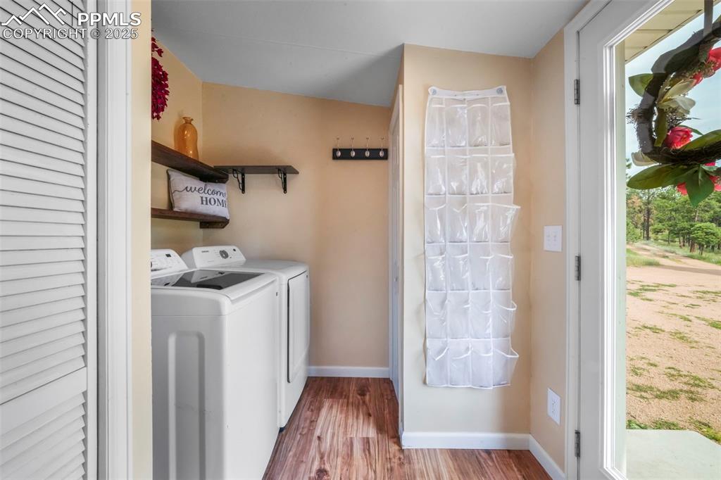 Image 39 of 50: Washroom featuring wood finished floors and washer and clothes dryer