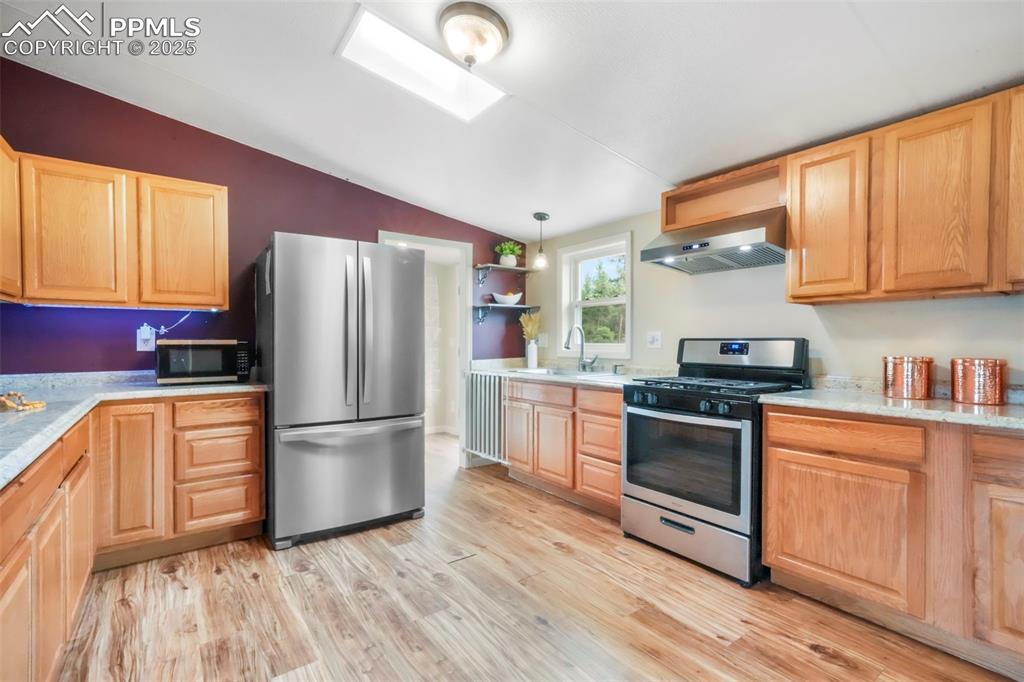 Image 6 of 50: Kitchen with open shelves, stainless steel appliances, a skylight, vaulted