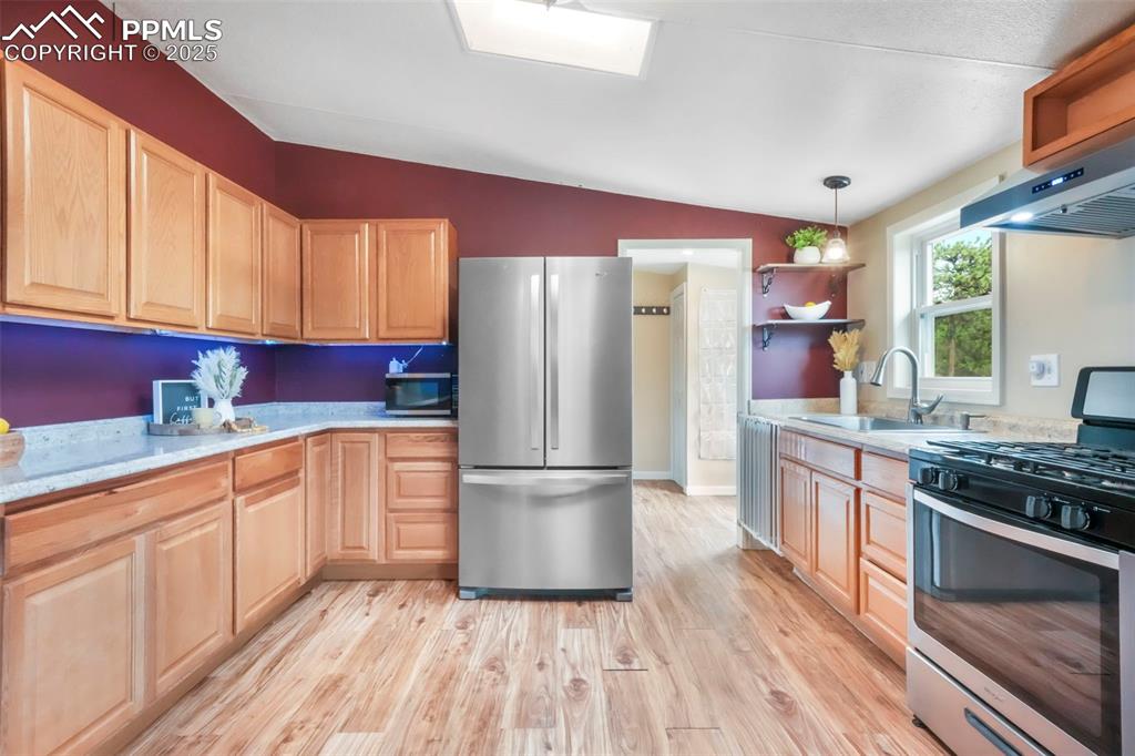 Image 8 of 50: Kitchen with open shelves, stainless steel appliances, vaulted ceiling, lig
