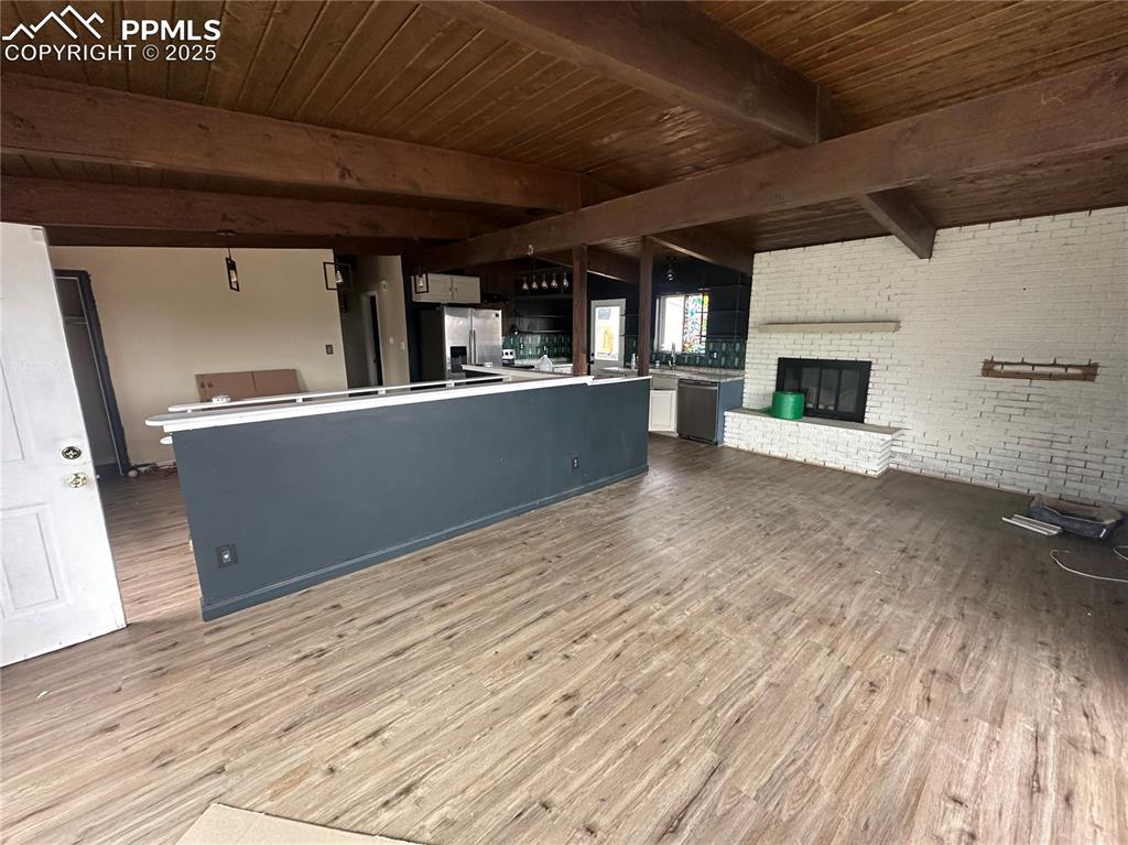 Image 3 of 14: Unfurnished living room with brick wall, light wood-style flooring, a woode