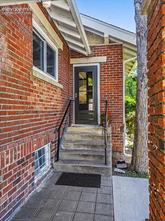 Image 21 of 27: Brick exterior with a walk-out kitchen covered entry on side of home concre