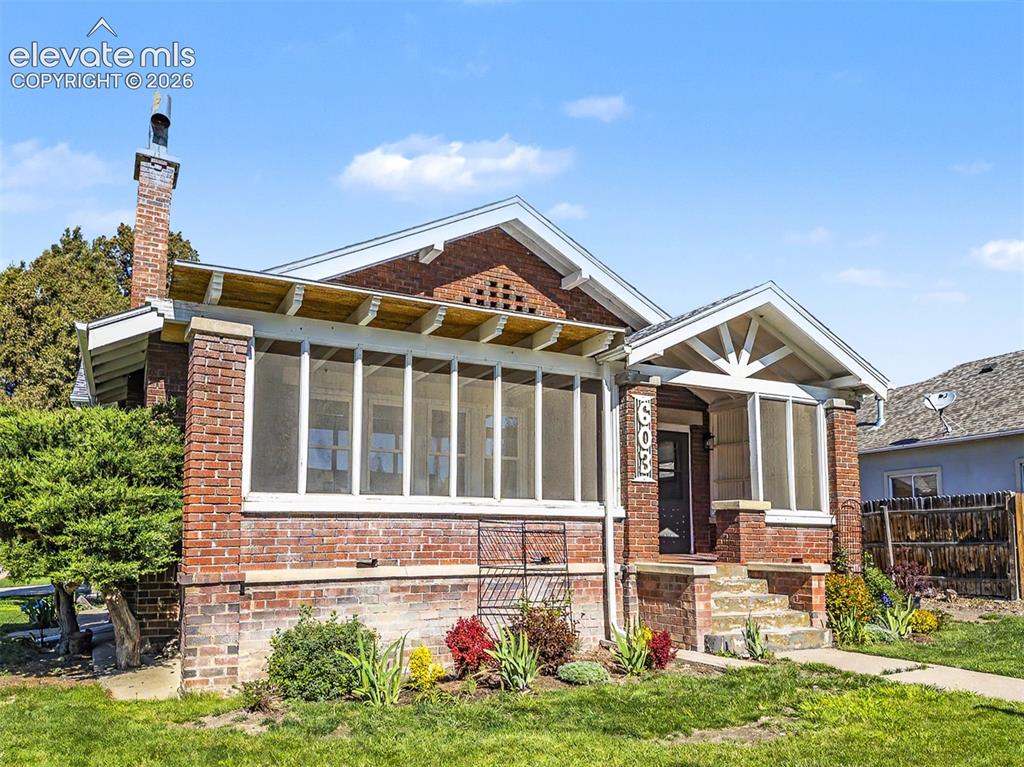 Image 22 of 27: Brick exterior featuring a screened porch and covered entry with exposed ra