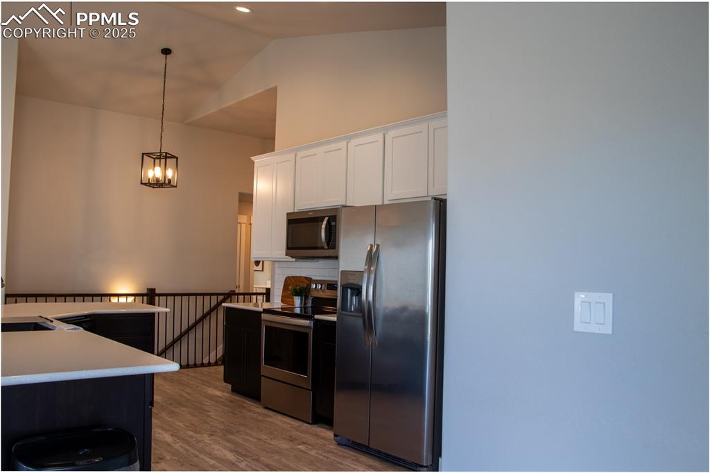 Image 11 of 30: Kitchen with appliances with stainless steel finishes, pendant lighting, wh
