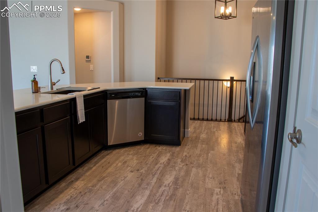 Image 12 of 30: Kitchen with appliances with stainless steel finishes, light wood-type floo