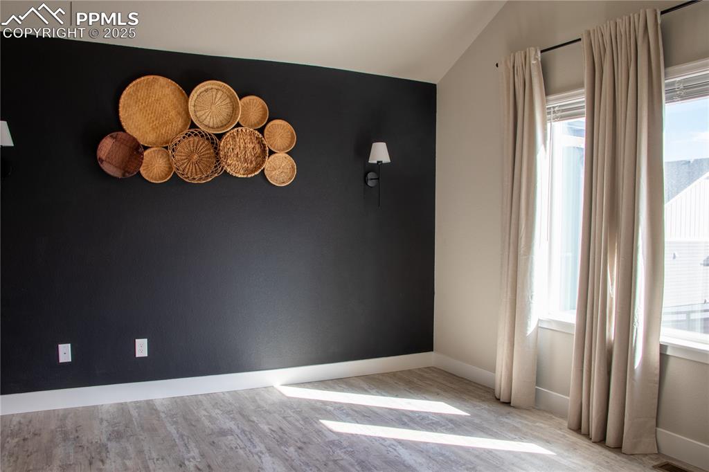 Image 15 of 30: Spare room featuring light wood finished floors and vaulted ceiling