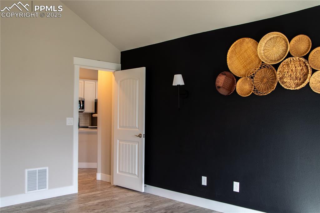 Image 17 of 30: Spare room featuring light wood-style flooring and vaulted ceiling