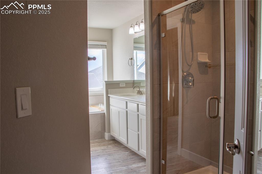 Image 19 of 30: Full bath with a shower stall, vanity, and light wood-style flooring