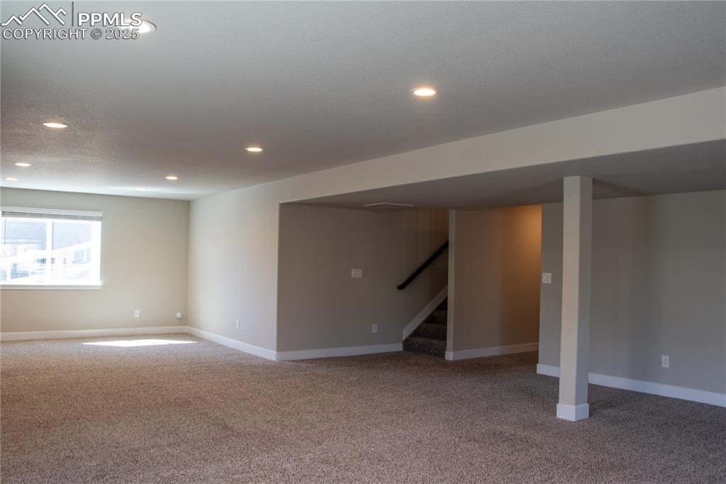 Image 26 of 30: Basement with light colored carpet, recessed lighting, and stairway