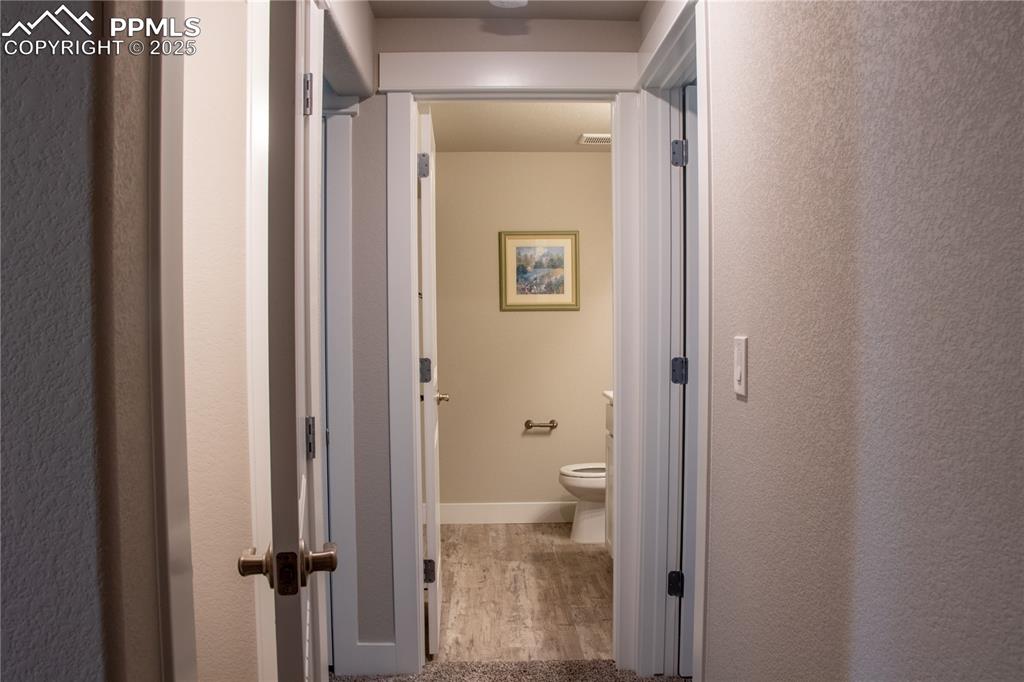 Image 28 of 30: Hallway with light wood-type flooring and a textured wall