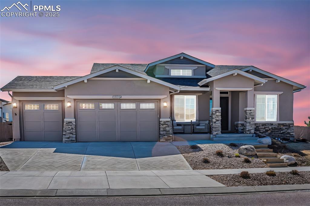 Caption: View of front of house featuring stone siding, a garage, stucco siding, and concrete driveway