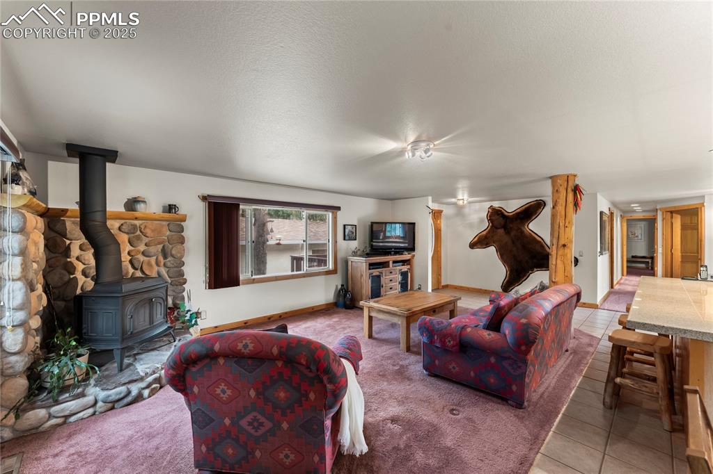 Image 16 of 42: Living room featuring a wood stove and custom stone surround 