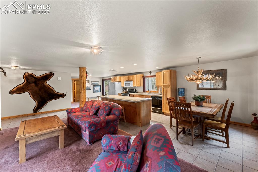 Image 19 of 42: Living room with light tile patterned floors, a chandelier, recessed lighti