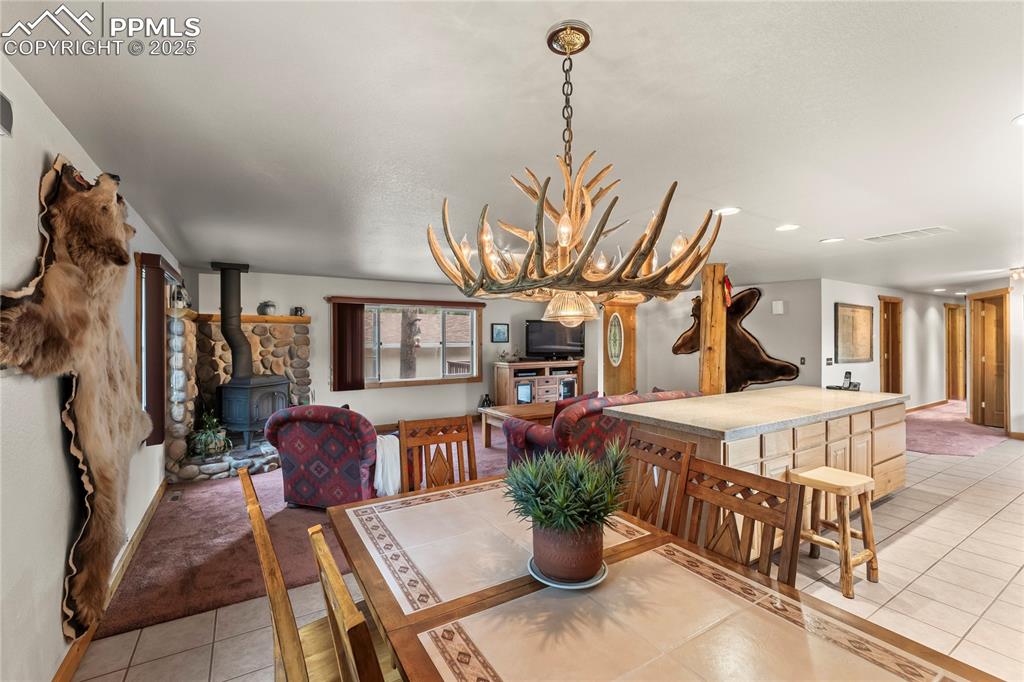 Image 22 of 42: Dining area featuring light tile patterned floors, a wood stove, and a chan