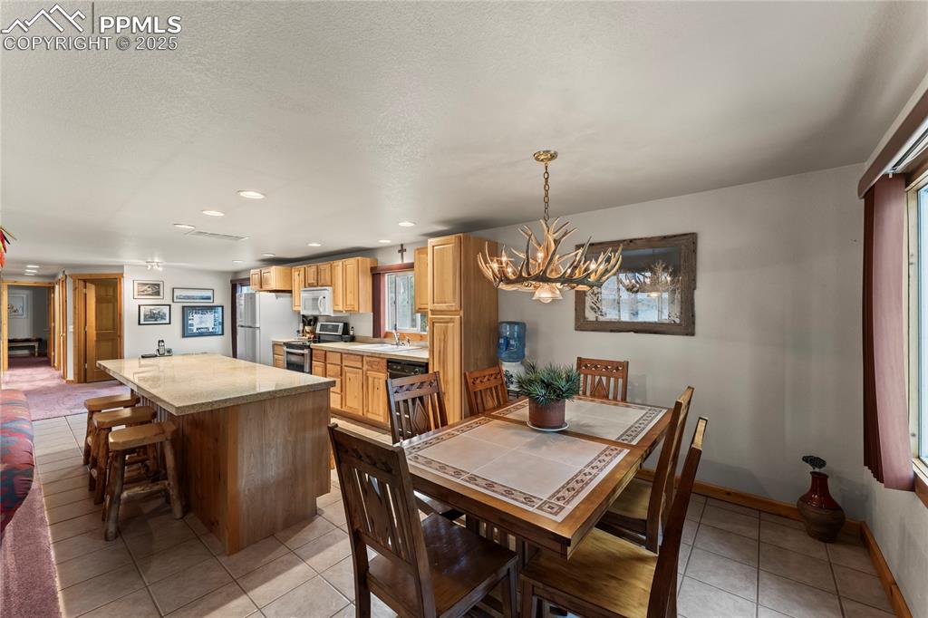 Image 23 of 42: Dining space with light tile patterned floors, a chandelier, recessed light