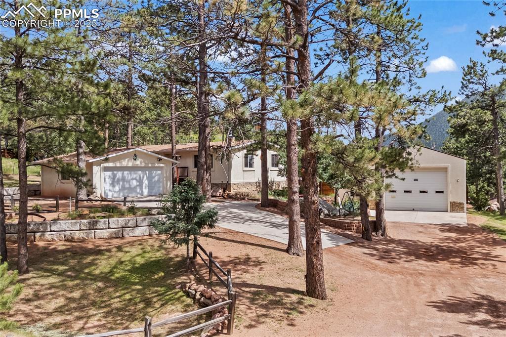 Image 38 of 42: View of front of house with a garage, dirt driveway, and stucco siding