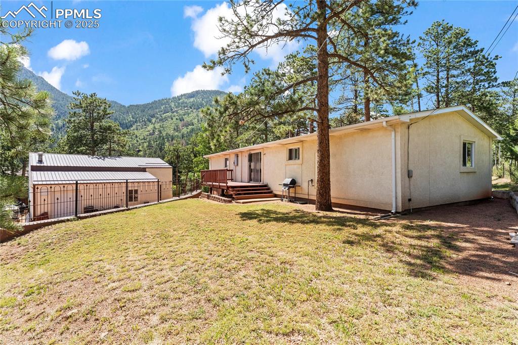 Image 5 of 42: Level backyard with a lawn, a deck with mountain view, stucco siding, and m