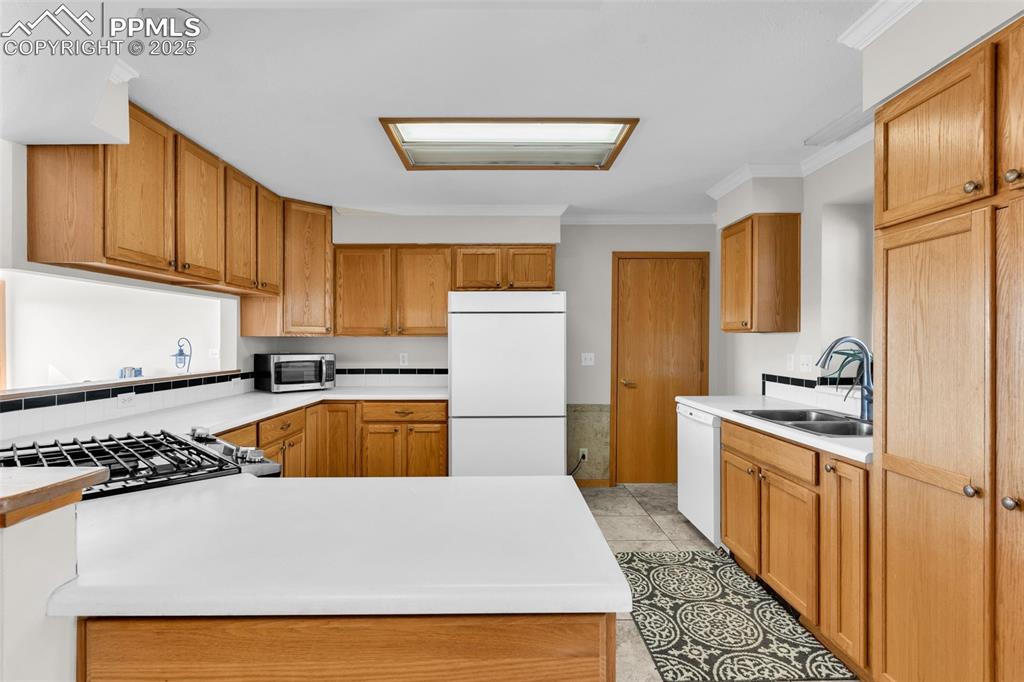 Image 14 of 50: Kitchen with light countertops, stainless steel appliances, crown molding, 