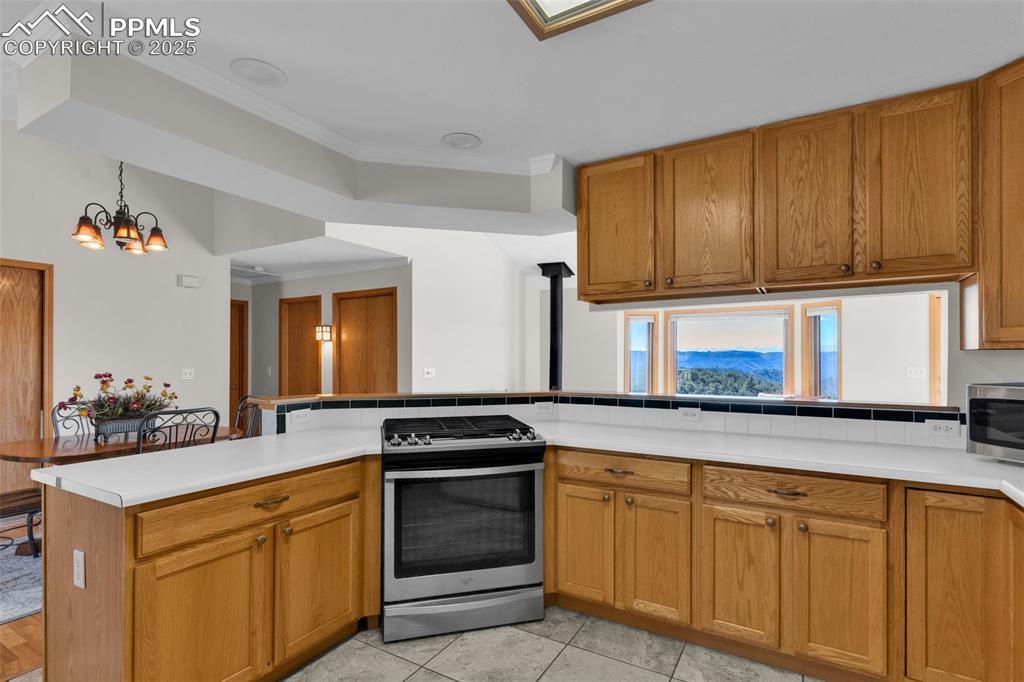 Image 16 of 50: Kitchen with ornamental molding, stainless steel appliances, brown cabinets
