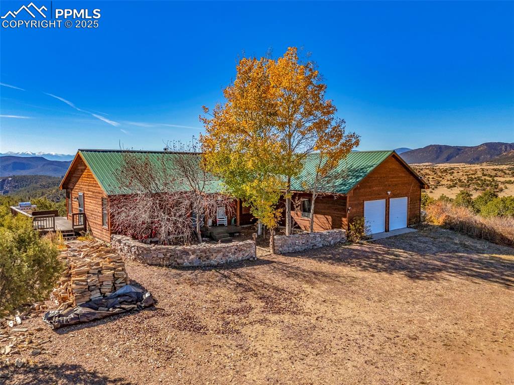 Image 2 of 50: View of front of property with a mountain view, a metal roof, dirt driveway
