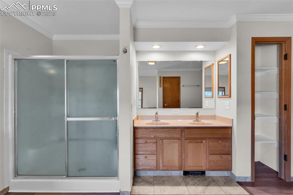Image 23 of 50: Full bath featuring crown molding, double vanity, a shower stall, and reces