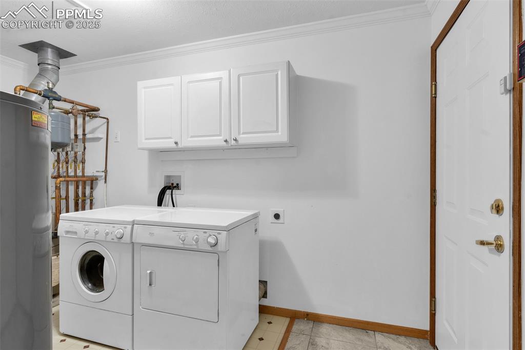 Image 29 of 50: Washroom with crown molding, cabinet space, electric water heater, and sepa