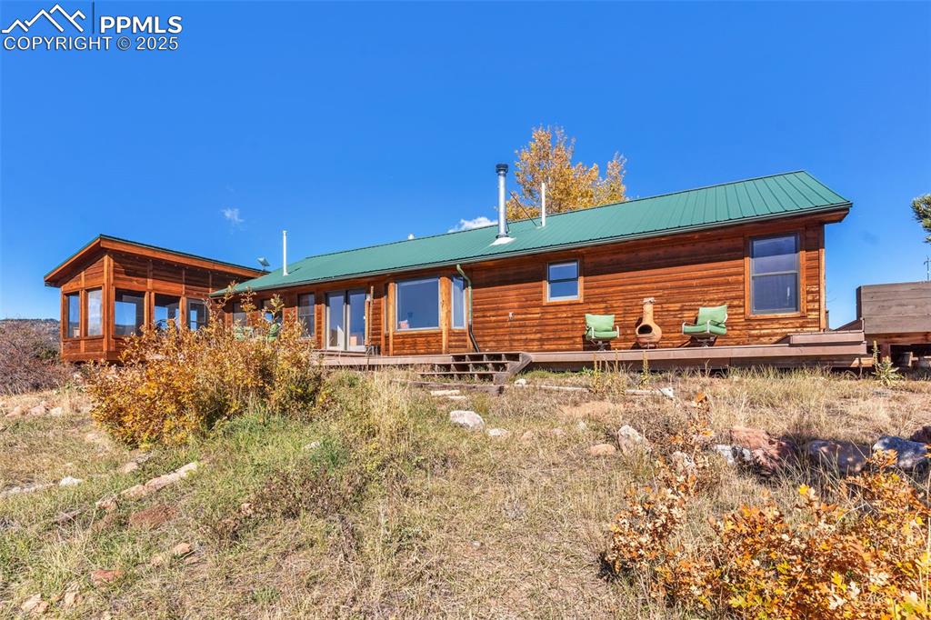 Image 38 of 50: Back of property with a metal roof and a wooden deck