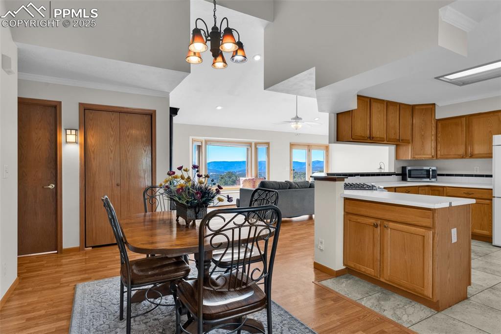 Image 4 of 50: Dining space featuring a ceiling fan, a chandelier, crown molding, light wo