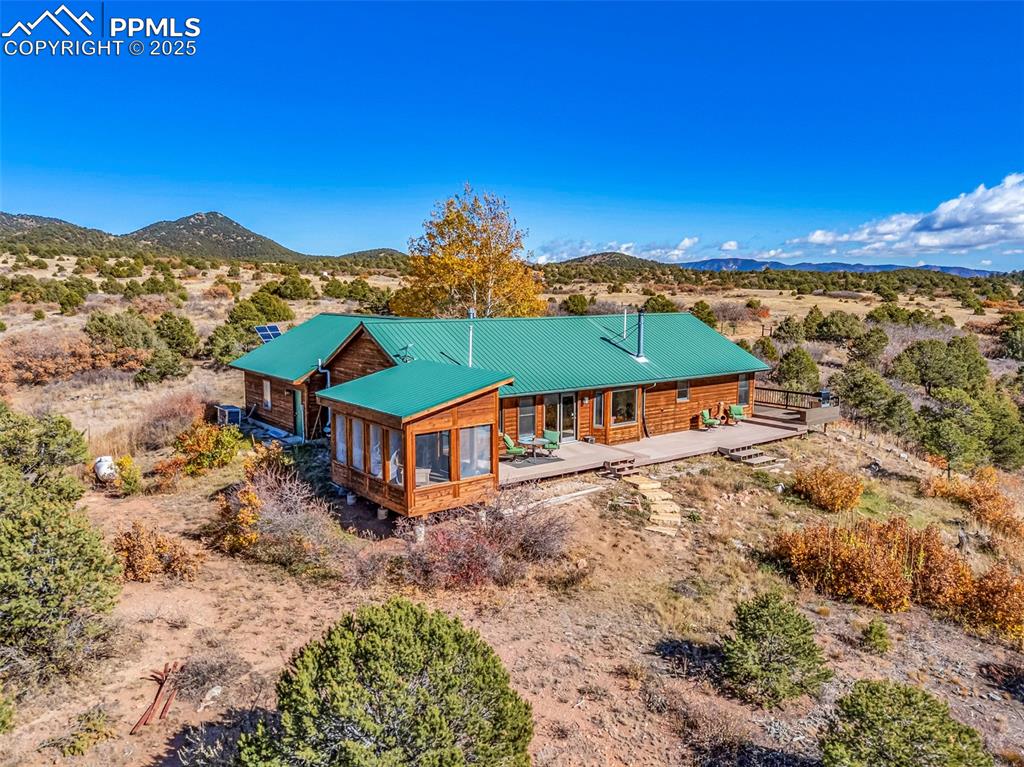 Image 43 of 50: Rear view of property with a mountain view, a metal roof, and view of deser