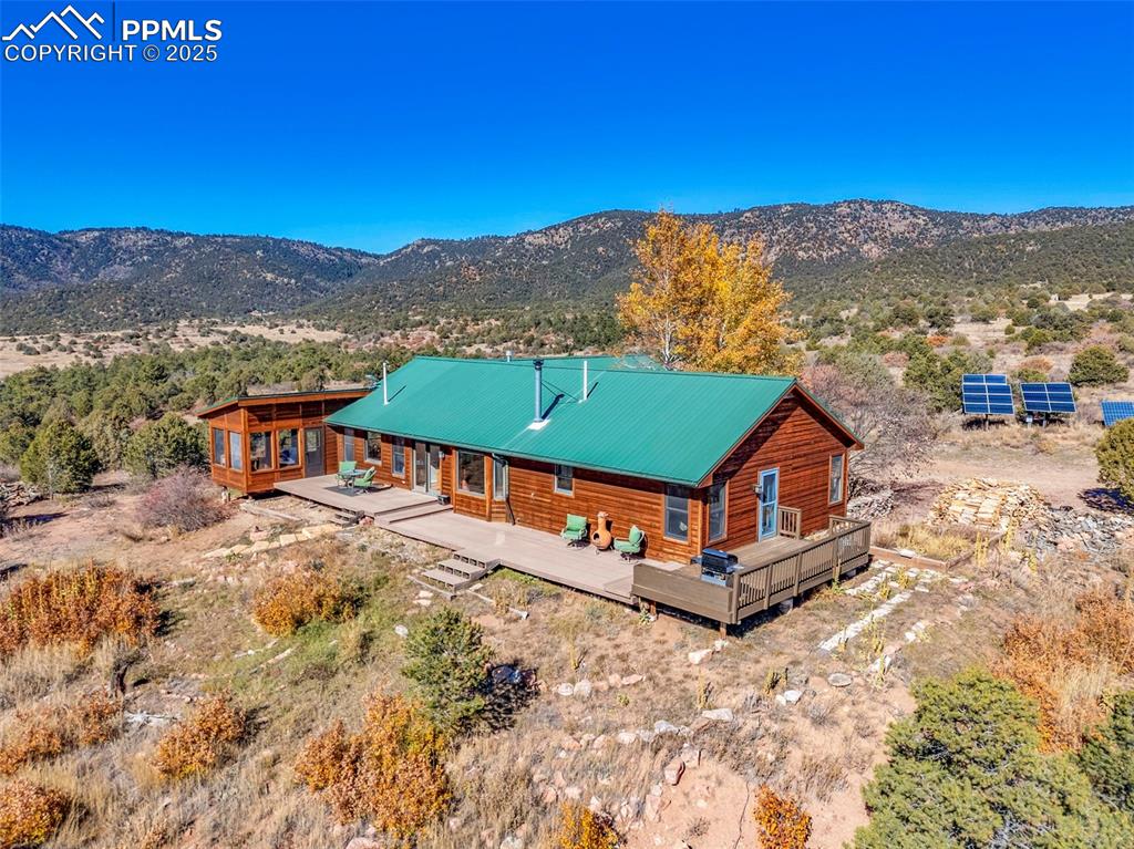 Image 44 of 50: Back of house with a deck with mountain view, solar panels, and a metal roo