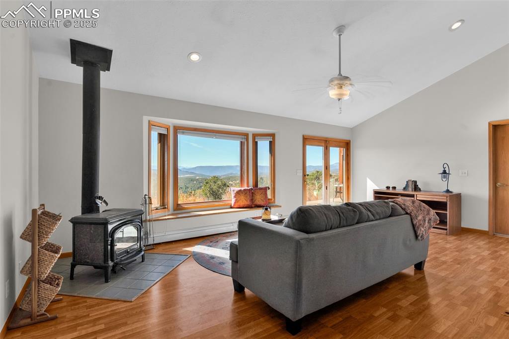 Image 7 of 50: Living area with a wood stove, lofted ceiling, light wood finished floors, 