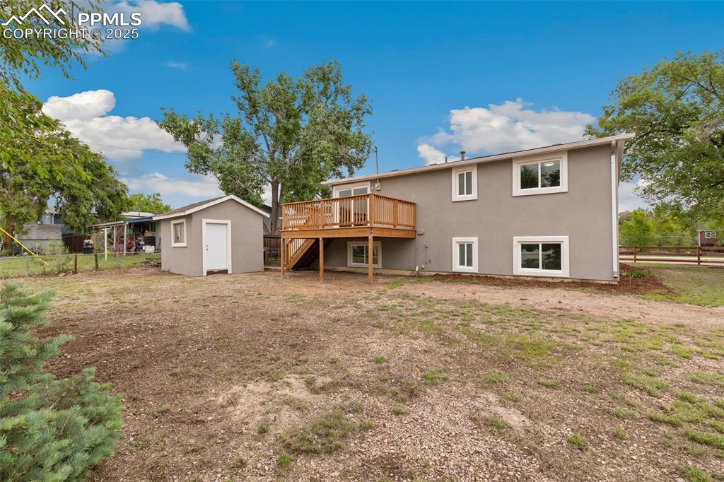 Image 18 of 18: Rear view of property featuring a wooden deck, stairway, a storage unit, an