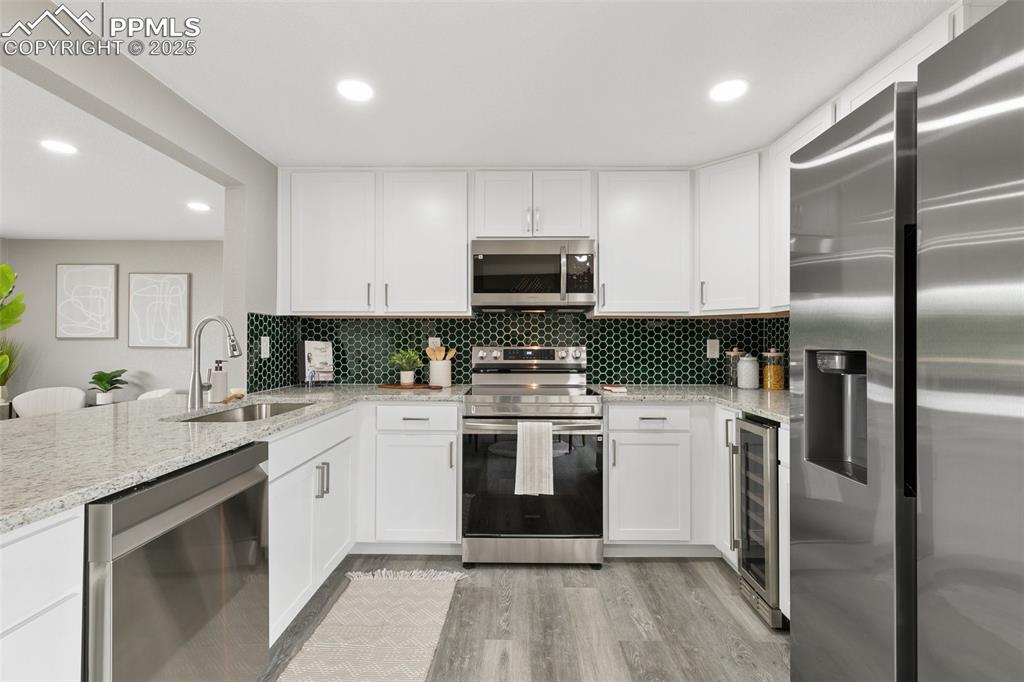 Image 7 of 18: Kitchen featuring stainless steel appliances, tasteful backsplash, wine coo