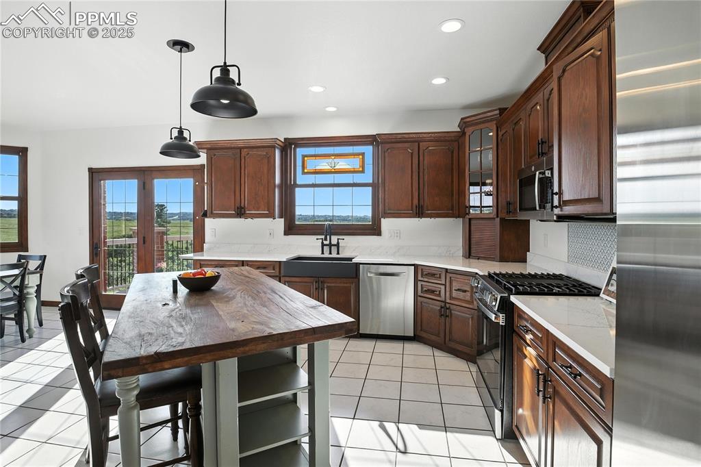 Image 13 of 50: Kitchen featuring appliances with stainless steel finishes, light tile patt