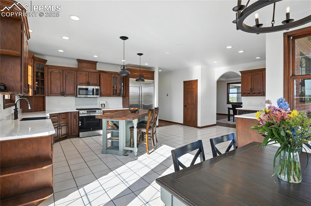 Image 14 of 50: Dining space with arched walkways, recessed lighting, light tile patterned