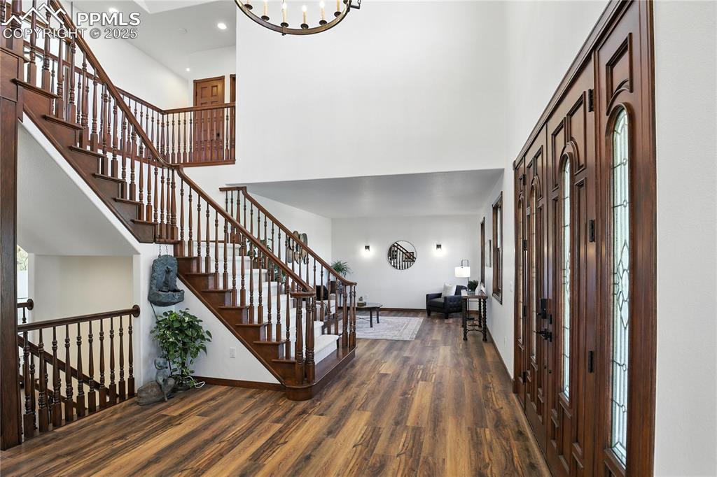 Image 8 of 50: Foyer featuring a towering ceiling, wood finished floors, stairway, recesse