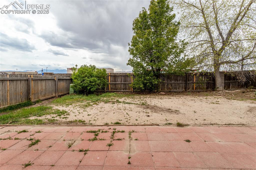 Image 37 of 43: Walk out the slider to backyard with stone patio and view of Pikes Peak.