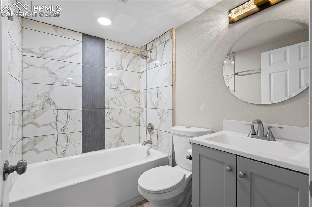Image 14 of 26: Bathroom featuring toilet, vanity, and bathtub / shower combination