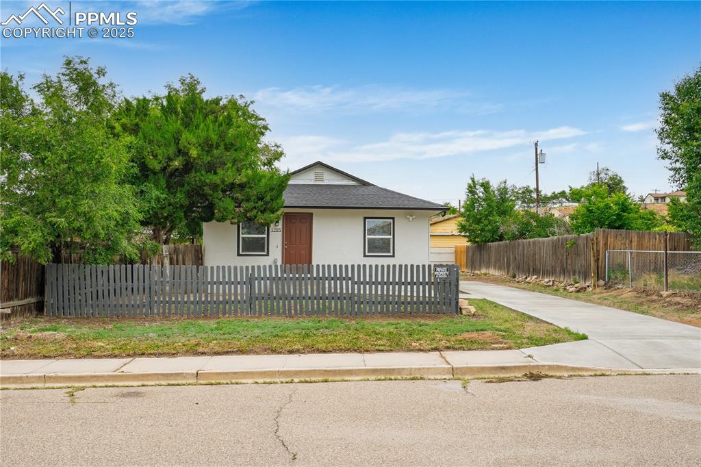 Image 2 of 26: View of front of home with stucco siding, a fenced front yard, roof with sh