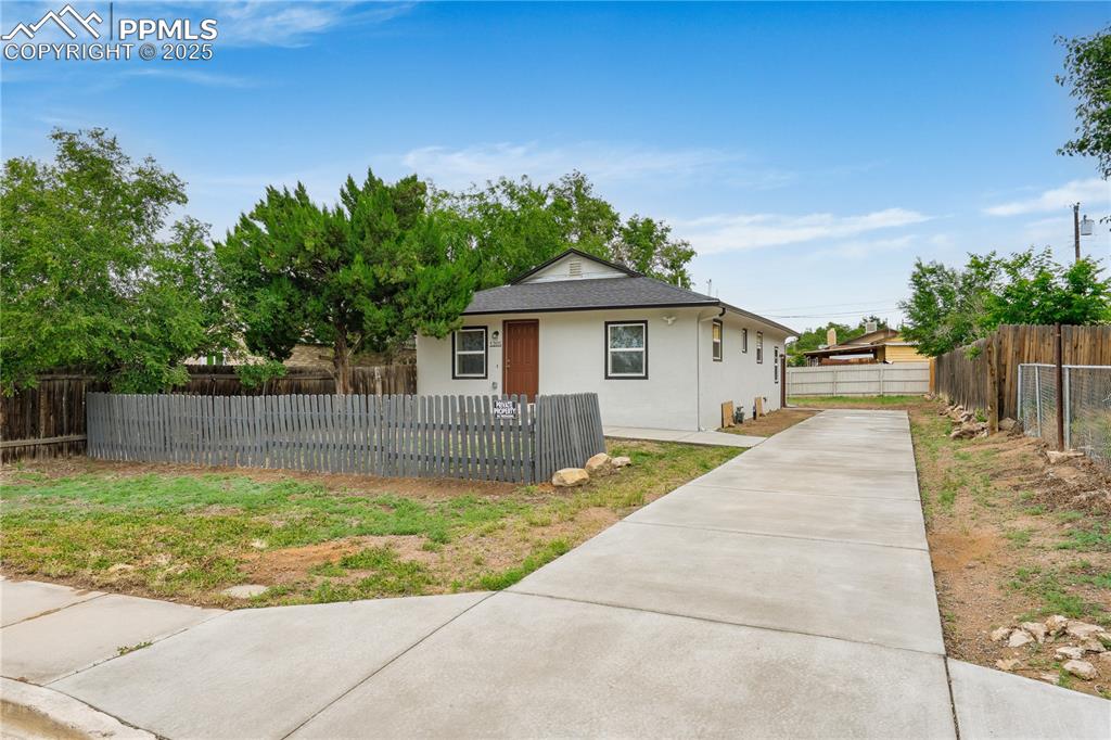 Image 3 of 26: Bungalow-style house featuring driveway, stucco siding, a fenced front yard
