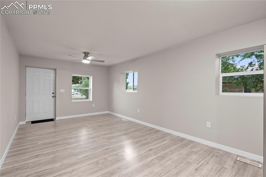 Image 7 of 26: Unfurnished room with a ceiling fan, baseboards, and light wood finished fl