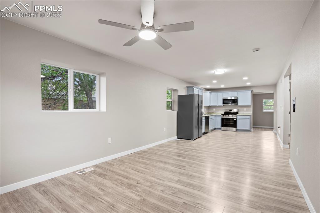 Image 8 of 26: Unfurnished living room with light wood-style floors, baseboards, a ceiling