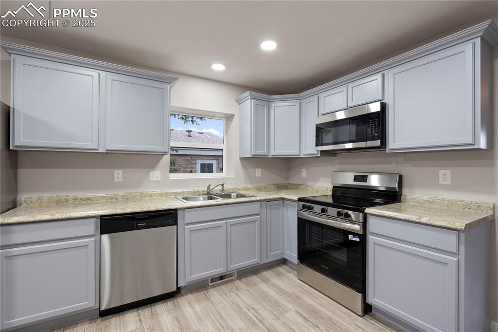 Image 9 of 26: Kitchen with appliances with stainless steel finishes, a sink, light counte